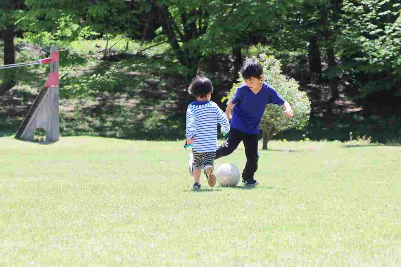公園でサッカーをする小学生